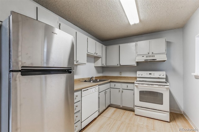 kitchen with white cabinetry, sink, white appliances, light hardwood / wood-style floors, and a textured ceiling