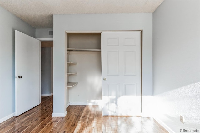 unfurnished bedroom with hardwood / wood-style floors, a closet, and a textured ceiling