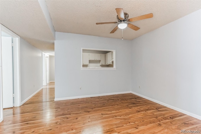 empty room featuring ceiling fan, a textured ceiling, and light wood-type flooring