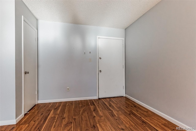 spare room featuring dark hardwood / wood-style floors and a textured ceiling