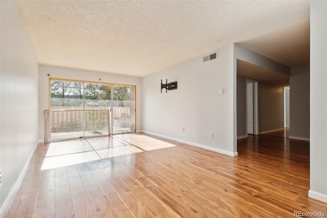 empty room with a textured ceiling and light wood-type flooring