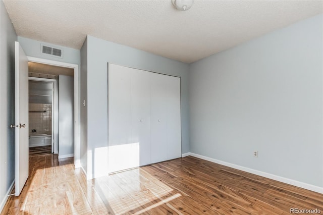 unfurnished bedroom featuring hardwood / wood-style flooring, a closet, and a textured ceiling