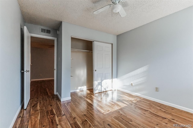 unfurnished bedroom with hardwood / wood-style flooring, ceiling fan, a closet, and a textured ceiling