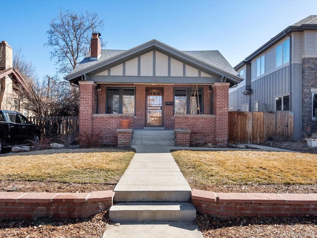 view of front of home with a front yard, brick siding, and fence