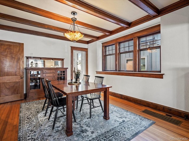 dining room with beam ceiling, hardwood / wood-style flooring, visible vents, and baseboards