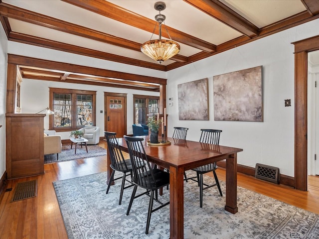 dining area featuring wood-type flooring, visible vents, baseboards, and beam ceiling