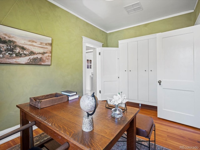 dining area featuring wood finished floors, visible vents, and crown molding