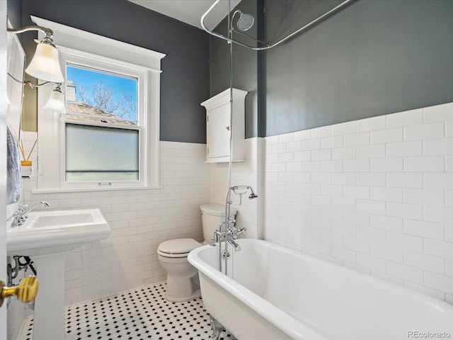 full bath featuring tile patterned flooring, toilet, tile walls, wainscoting, and a bathtub