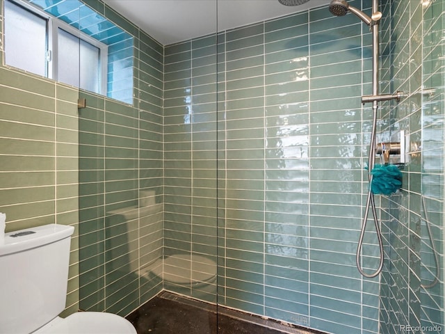 full bathroom with a tile shower and toilet