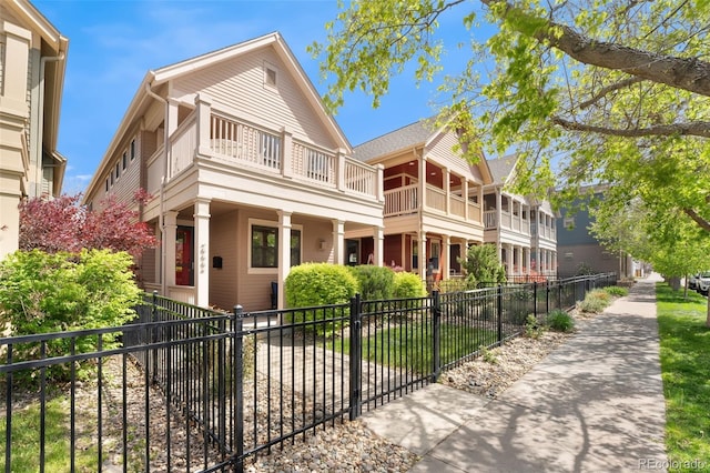 view of front of property featuring covered porch, a fenced front yard, and a balcony