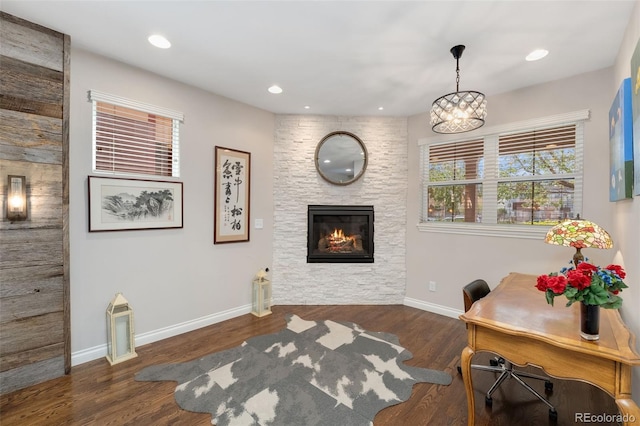 living room featuring an inviting chandelier, wood finished floors, a stone fireplace, baseboards, and recessed lighting