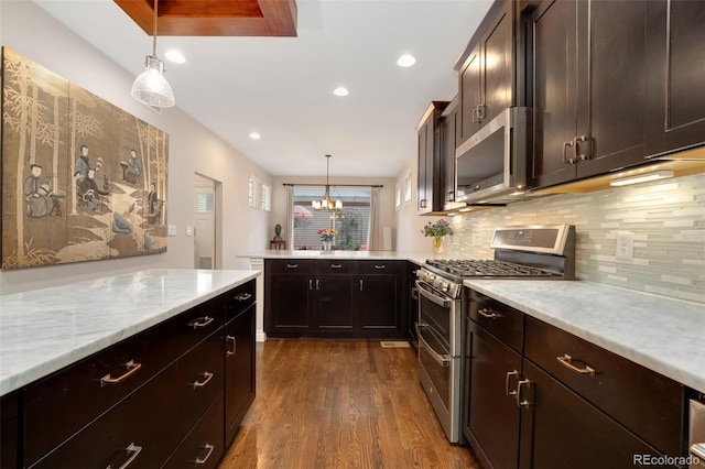 kitchen with backsplash, appliances with stainless steel finishes, hanging light fixtures, a peninsula, and dark wood-type flooring