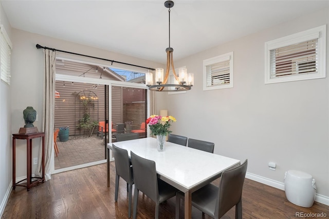 dining area featuring baseboards, a notable chandelier, and dark wood-type flooring