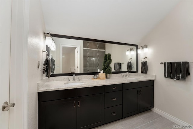 full bathroom with a sink, baseboards, vaulted ceiling, and double vanity