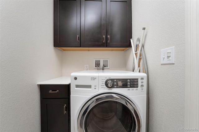 clothes washing area featuring cabinet space, washer / clothes dryer, and a textured wall