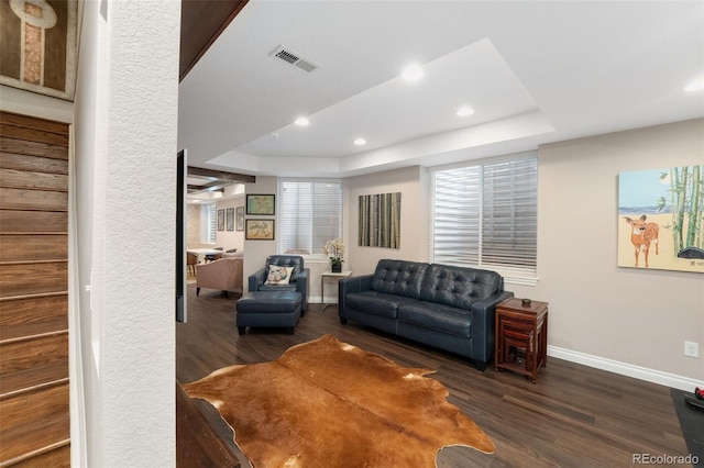living room featuring a raised ceiling, recessed lighting, baseboards, wood finished floors, and visible vents