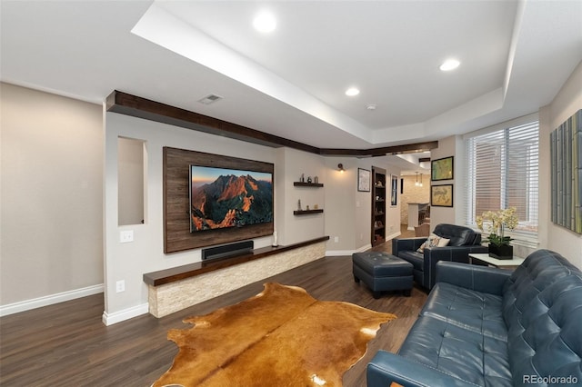 living room with visible vents, baseboards, a raised ceiling, and wood finished floors