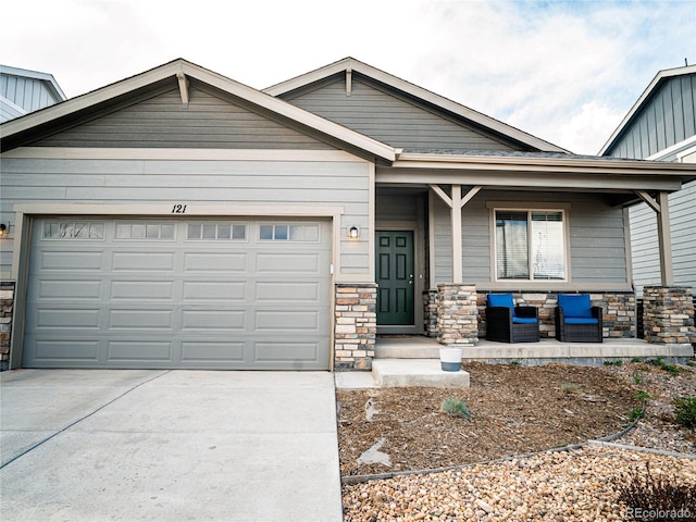 craftsman-style home featuring covered porch, board and batten siding, driveway, an attached garage, and stone siding