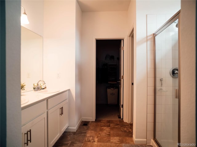 full bath with double vanity, a walk in closet, a sink, and a stall shower
