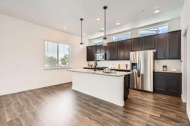 6791 Navajo Ct, Denver, CO 80221 - kitchen featuring stainless steel appliances, a center island with sink, dark brown cabinets, dark wood finished floors, and light stone countertops
