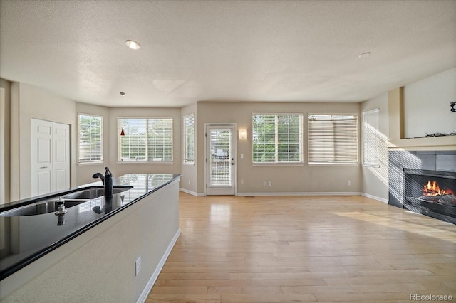 9602 Indian Wells Dr, Lone Tree, CO 80124 - kitchen with a textured ceiling, light wood finished floors, baseboards, a fireplace, and a sink