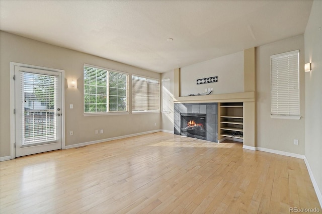 9602 Indian Wells Dr, Lone Tree, CO 80124 - unfurnished living room featuring light wood finished floors, baseboards, and a tiled fireplace