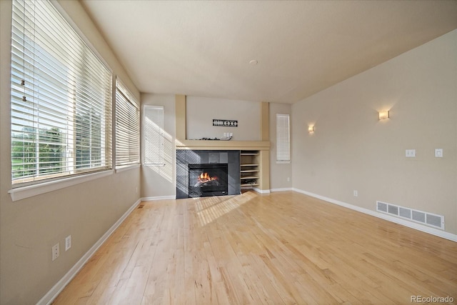 9602 Indian Wells Dr, Lone Tree, CO 80124 - unfurnished living room featuring hardwood / wood-style flooring, a tiled fireplace, baseboards, and plenty of natural light