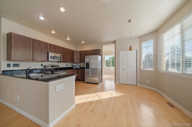 9602 Indian Wells Dr, Lone Tree, CO 80124 - kitchen with stainless steel appliances, a sink, dark countertops, dark brown cabinets, and light wood finished floors