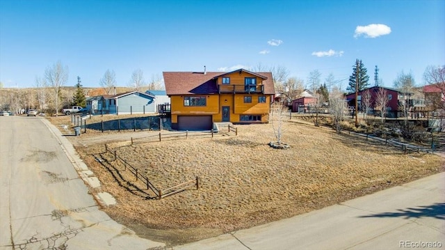 view of front facade featuring an attached garage, a residential view, and fence