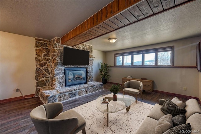 living room with a stone fireplace, a textured ceiling, and wood finished floors