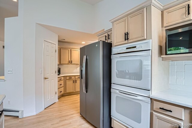 1851 S Marshall Cir, Lakewood, CO 80232 - kitchen with stainless steel appliances, baseboard heating, backsplash, light wood-type flooring, and light countertops