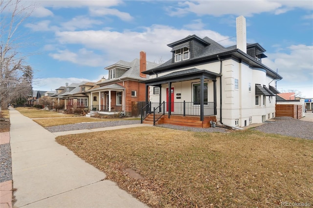 view of front of property featuring a porch, a chimney, and a front lawn