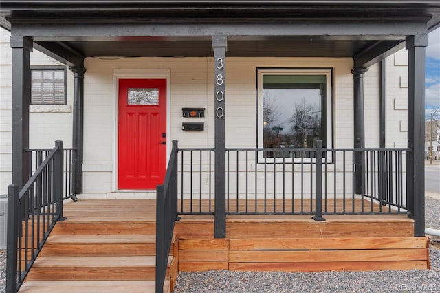 property entrance featuring brick siding and a porch