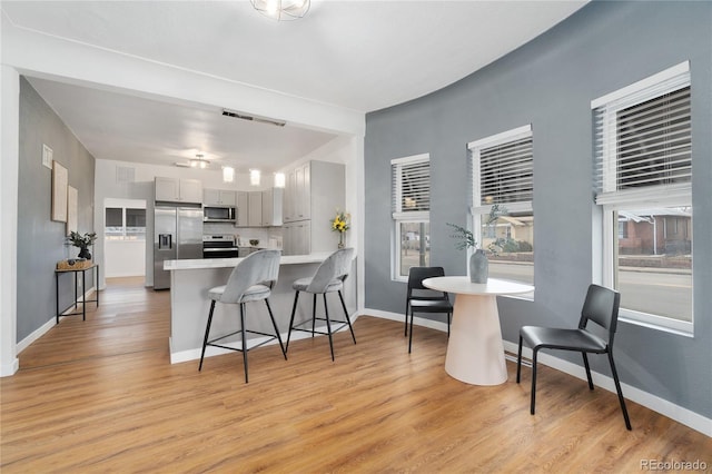 kitchen with light wood-style flooring, a breakfast bar, a peninsula, stainless steel appliances, and light countertops