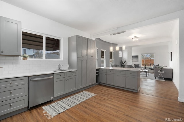 kitchen with a sink, dishwasher, a peninsula, and gray cabinetry