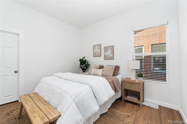 bedroom with wood finished floors, visible vents, and baseboards