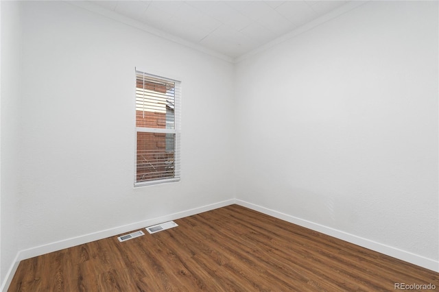 spare room with ornamental molding, visible vents, dark wood finished floors, and baseboards