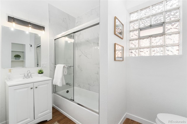 full bath featuring toilet, bath / shower combo with glass door, wood finished floors, vanity, and baseboards