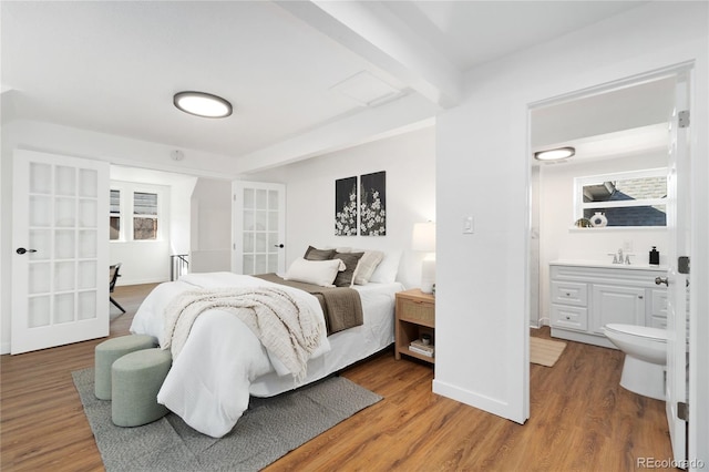 bedroom featuring a sink, french doors, beamed ceiling, and wood finished floors