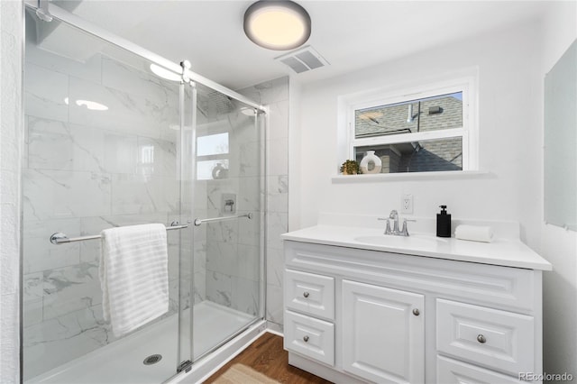 bathroom featuring visible vents, vanity, a marble finish shower, and wood finished floors