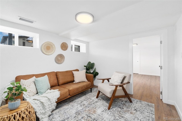 living room with baseboards, visible vents, and wood finished floors