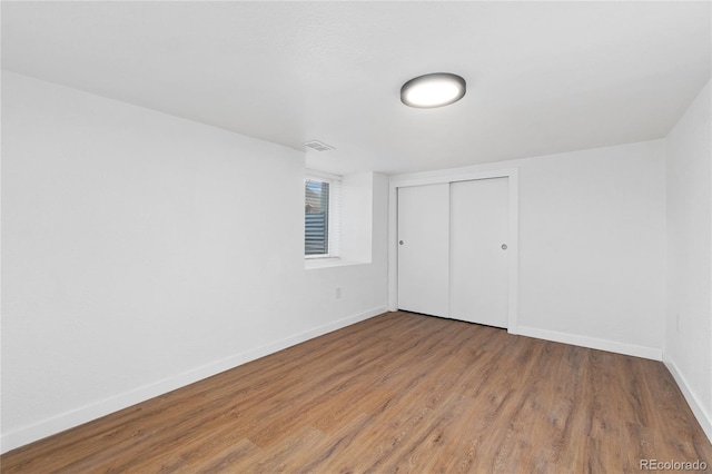 unfurnished bedroom with a closet, baseboards, and wood finished floors