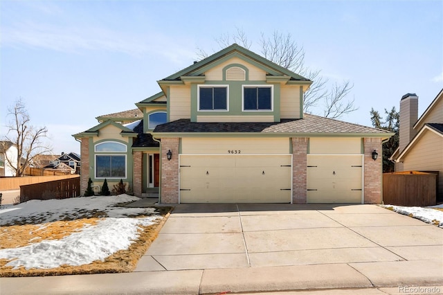 traditional-style house with fence, concrete driveway, and brick siding