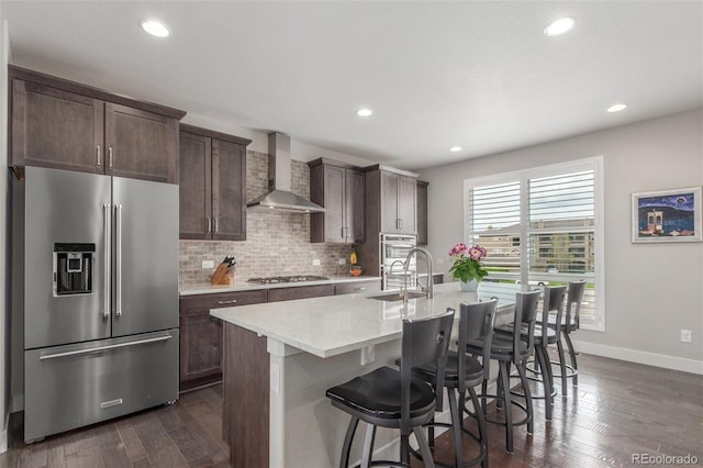 15843 E Broncos Pl, Englewood, CO 80112 - kitchen with stainless steel appliances, wall chimney exhaust hood, a kitchen island with sink, light countertops, and baseboards