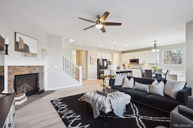 living room featuring a fireplace, light hardwood / wood-style flooring, and ceiling fan