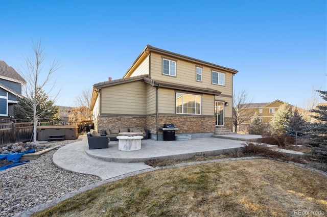 rear view of house with an outdoor fire pit, a hot tub, and a patio area