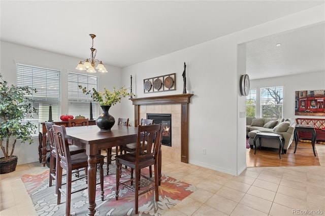 tiled dining area with a tiled fireplace and a chandelier