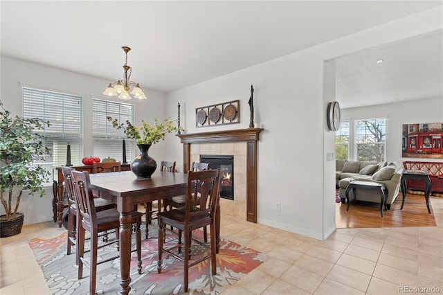 6470 S Ider St, Aurora, CO 80016 - dining area with light tile patterned floors, a chandelier, a fireplace, and baseboards