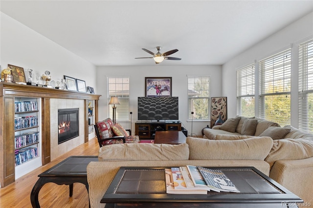 living room with ceiling fan, a tile fireplace, and light hardwood / wood-style floors