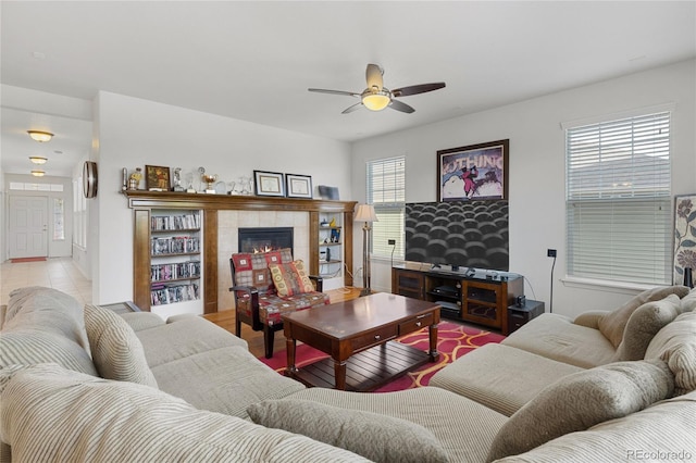 living room featuring light hardwood / wood-style flooring, ceiling fan, and a tile fireplace